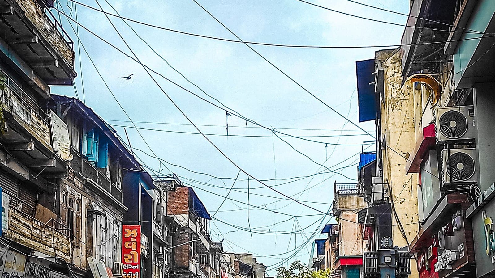 A busy shopping street in Ahmedabad lined with small shopfronts and hanging signage